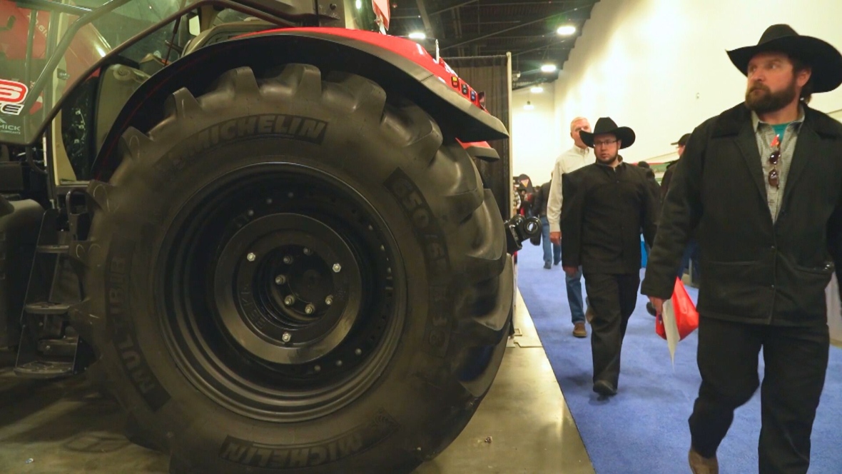 A man walks past a large tractor tire.